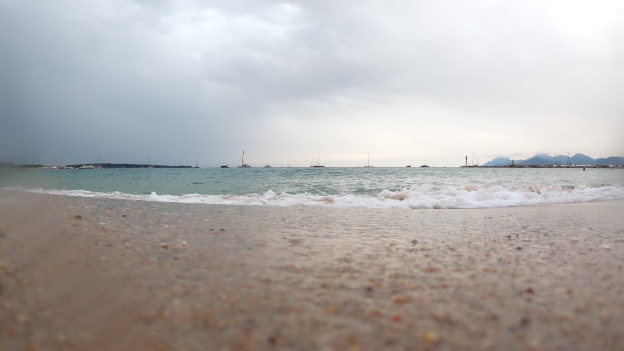 Waves hitting the shore on the beach on a cloudy day