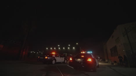 turning fpv shot of 2 police cars with flashing lights pulling over a car at night time