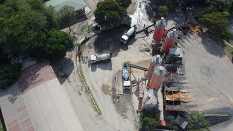 concrete mixer trucks moving and working on industrial zone or construction site, aerial view with forward motion