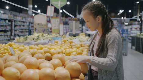 girl choosing grapefruit in a grocery store
