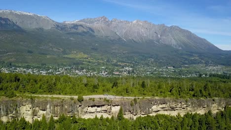 Trucking-left-of-El-Bolsón-valley-surrounded-by-woods-with-Piltriquitron-Hill-in-background,-Patagonia-Argentina