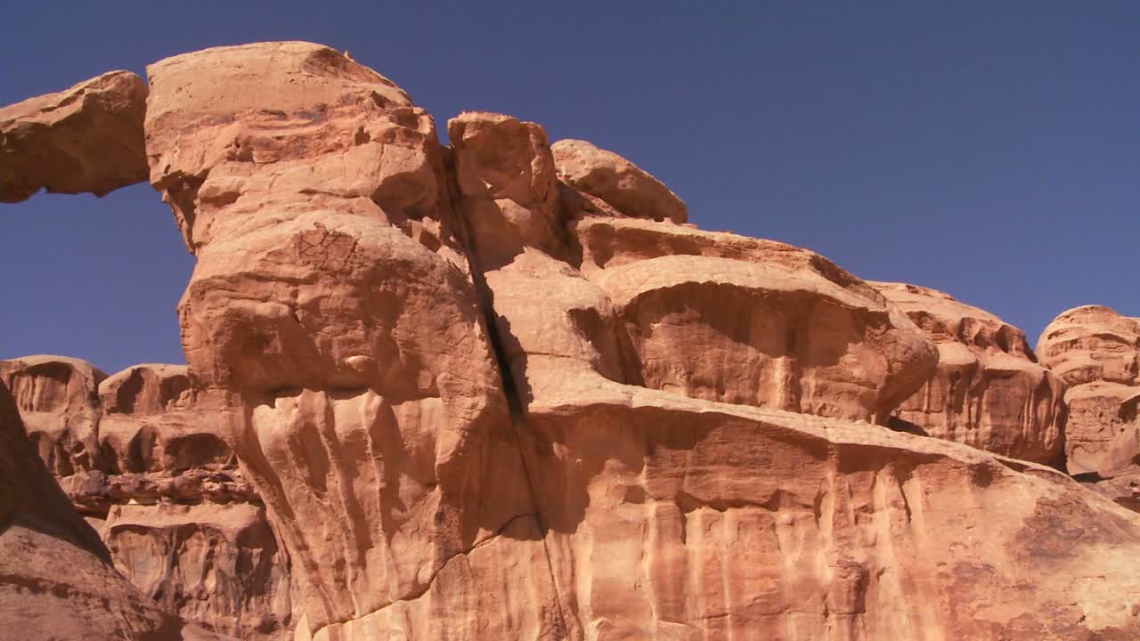 panorámica a través de una increíble formación de arco en el desierto de sadi en wadi rum jordania con un hombre beduino caminando a través