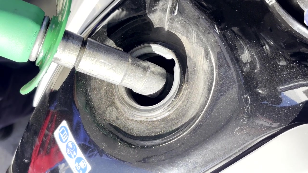 Nærbillede af en brændstofpistol indsat i en motorcykeltank for at fylde benzin på.