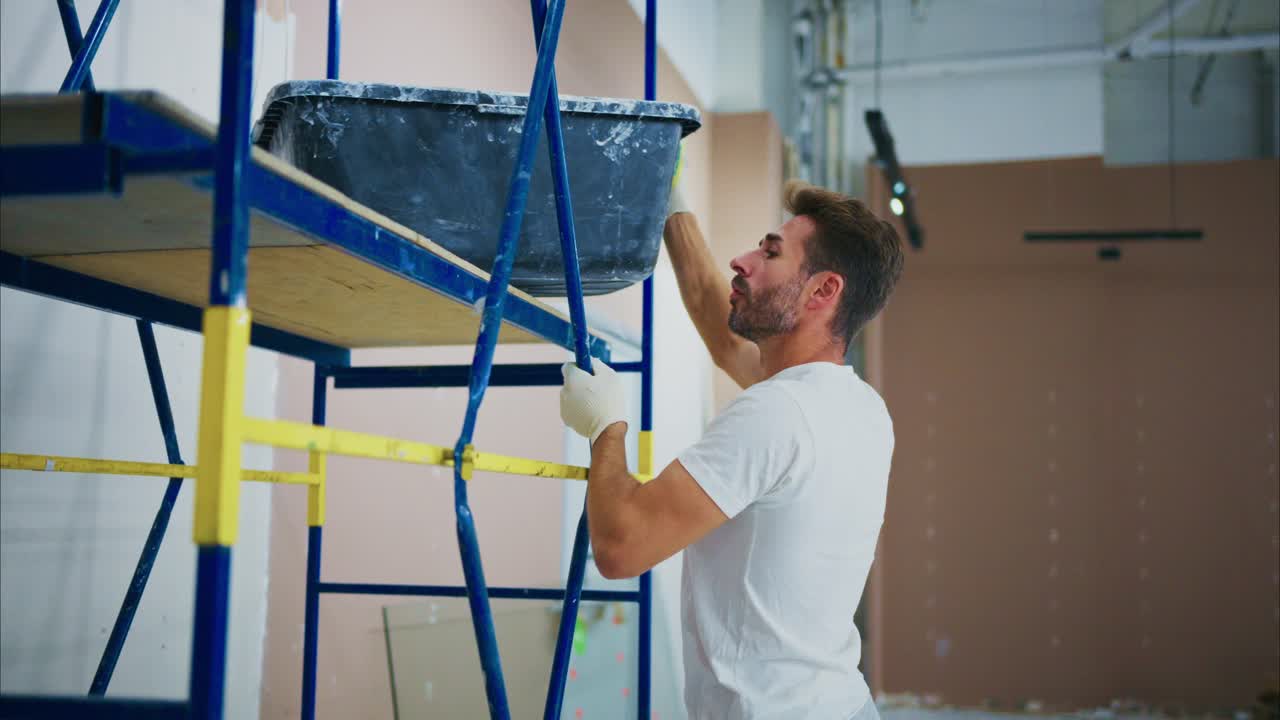 A Worker in a Construction Setting Adjusting a Scaffold, Preparing for Painting and Renovation Tasks in a Home Improvement Project