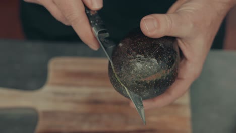 close-up on hands cutting avocado with steel knife