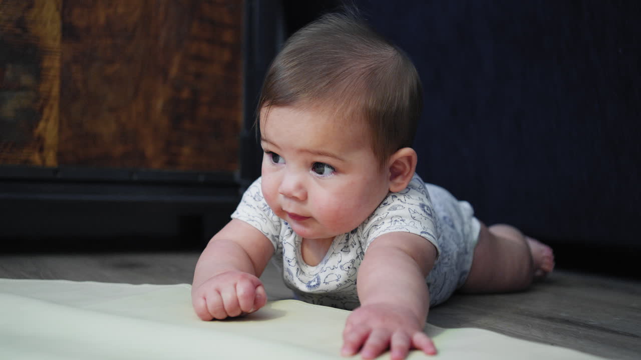 bebé sonriendo en el suelo mientras está en su estómago aprendiendo a arrastrarse