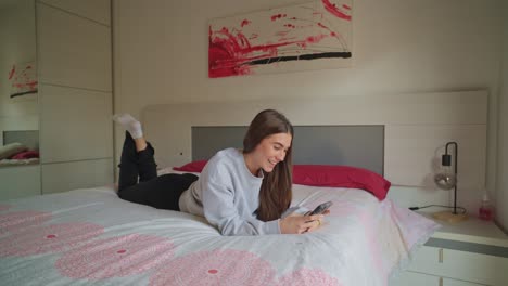 woman using smartphone lying on bed