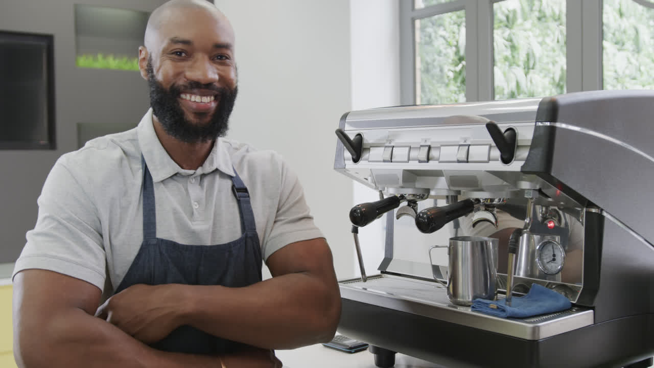 retrato de un feliz barista afroamericano con los brazos cruzados sonriendo en un café, en cámara lenta