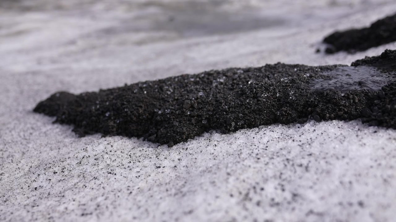 Melting Water From Glacier Moving Black Lava Rocks and Sand on Ice, Close Up 60fps