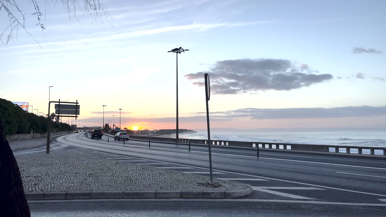 카르카벨로스의 요새 뒤에서 환상적인 해가 뜨고, 차들이 해안가를 따라 돌아다니고 있습니다.