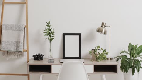 Black-frame-with-copy-space-on-white-background-with-plant-on-desk-against-white-wall