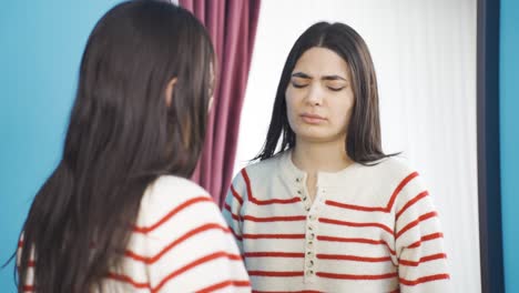 Unhappy-young-woman-looking-at-braces-in-mirror.