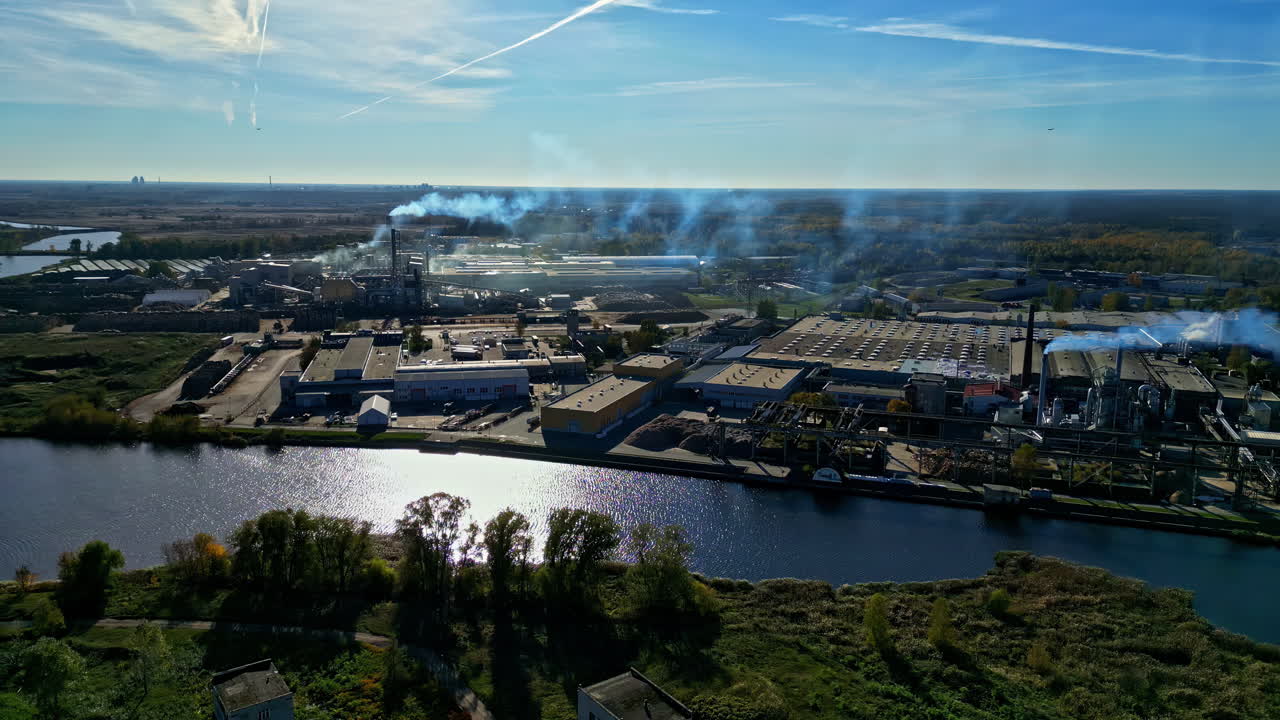 Industrial area with smokestacks, river, and blue sky, day