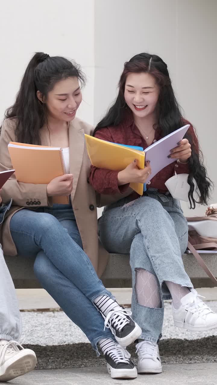 two asian girl students talking at break time sitting on campus
