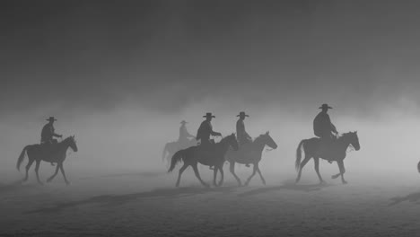 cowboys on horses in a foggy landscape