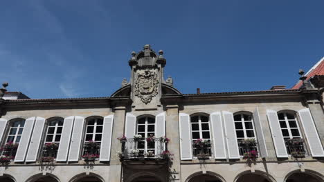 edificio europeo histórico bajo un cielo azul brillante con detalles ornamentados y balcones alineados con flores