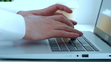 a man is working at a laptop, pressing the keyboard buttons with his fingers. close-up