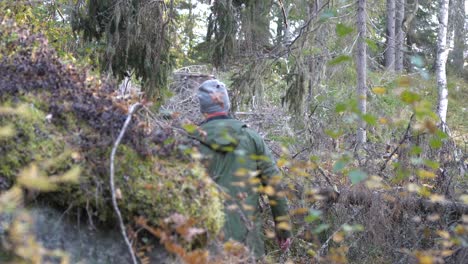 Brave-man-walking-through-dense-Scandinavian-forest,-static-back-view