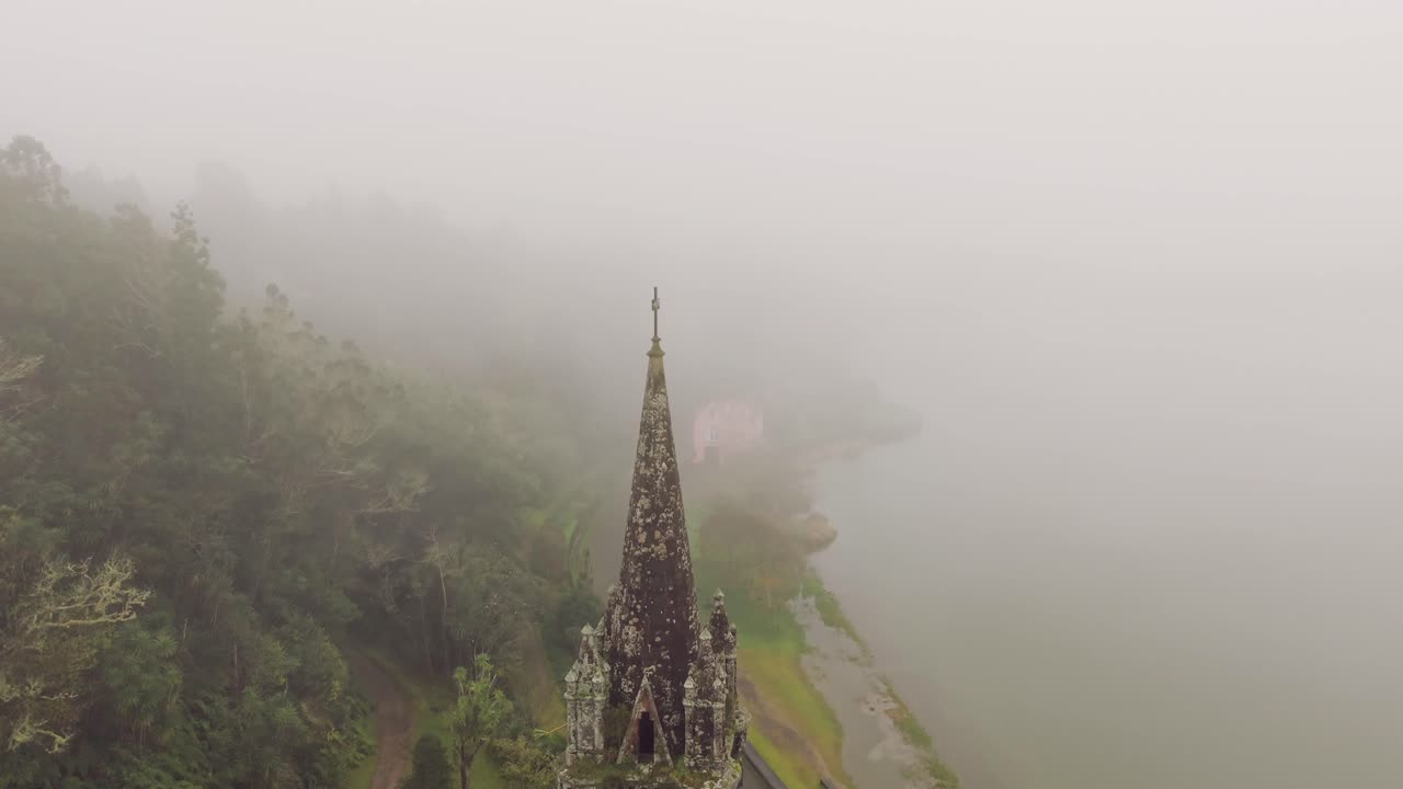 Close aerial view of chapel tower near Furnas Lake in misty landscape Sao Miguel Azores