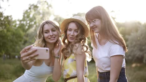 Gruppe-Von-Drei-Schönen-Freundinnen,-Die-Draußen-Ein-Picknick-Machen.-Sie-Machen-Selfie-Fotos-Vom-Smartphone.-Die-Sonne-Scheint-Auf-Den-Hintergrund