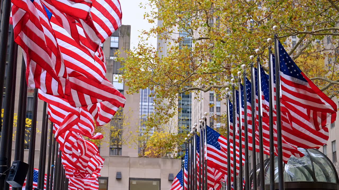 New York, USA, 6 November 2025: Plenty of American flags in two rows outdoors. Windy autumn day in New York, USA. Facades of the buildings at backdrop