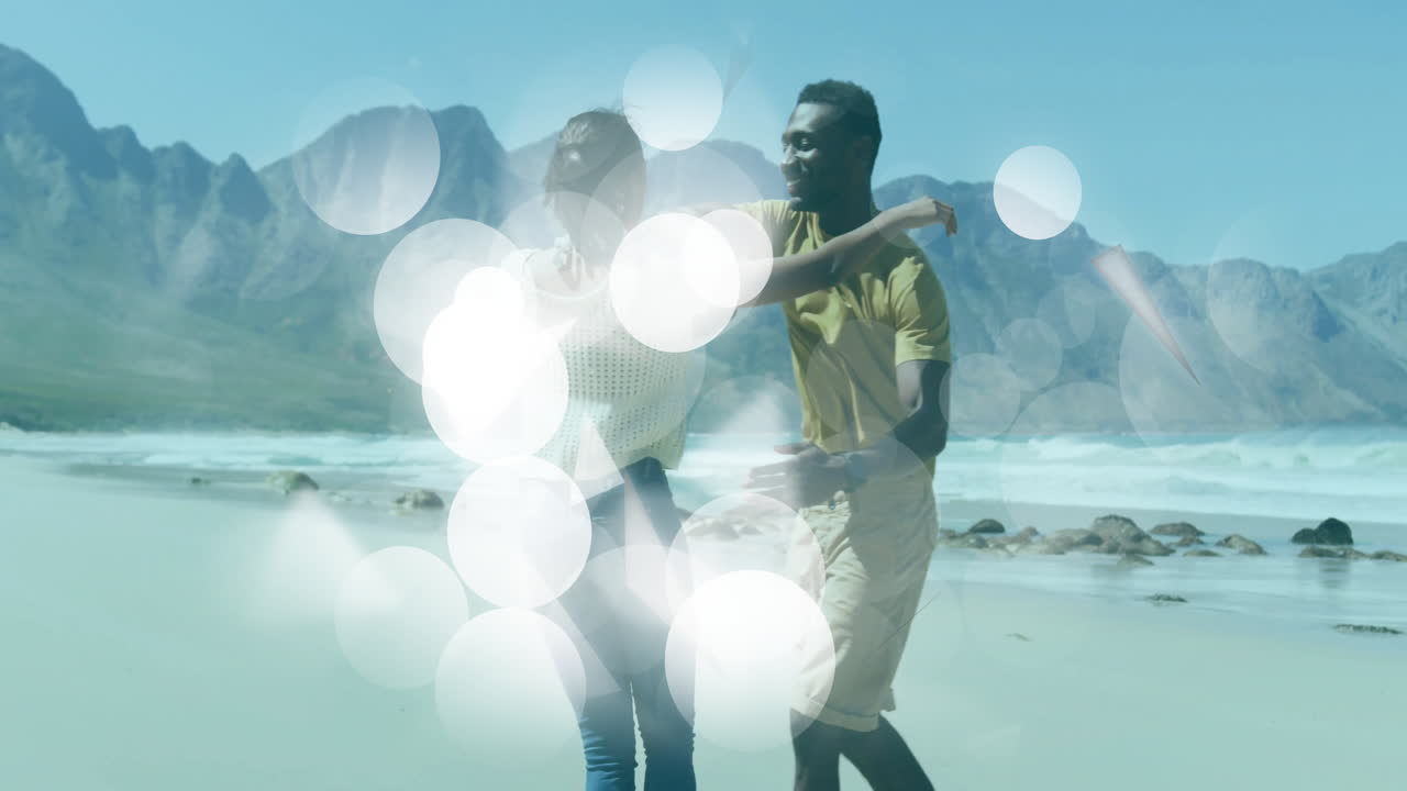 Dancing joyfully on beach, couple surrounded by bright bokeh lights animation