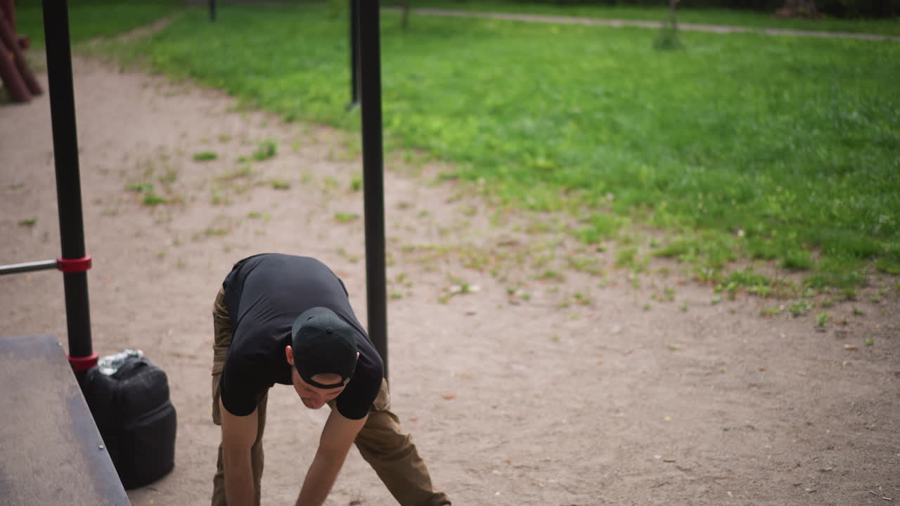 Man Checks Equipment, Person Adjusts Grip And Stance For Workout, Man Setting Up Calisthenics Routine At Outdoor Park, Individual Arranging Grip And Posture To Begin Bodyweight Training Outdoors