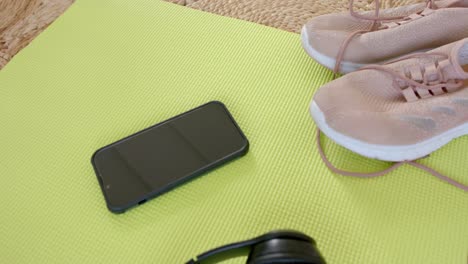 close up of training shoes, smartphone and headphones on mat, slow motion