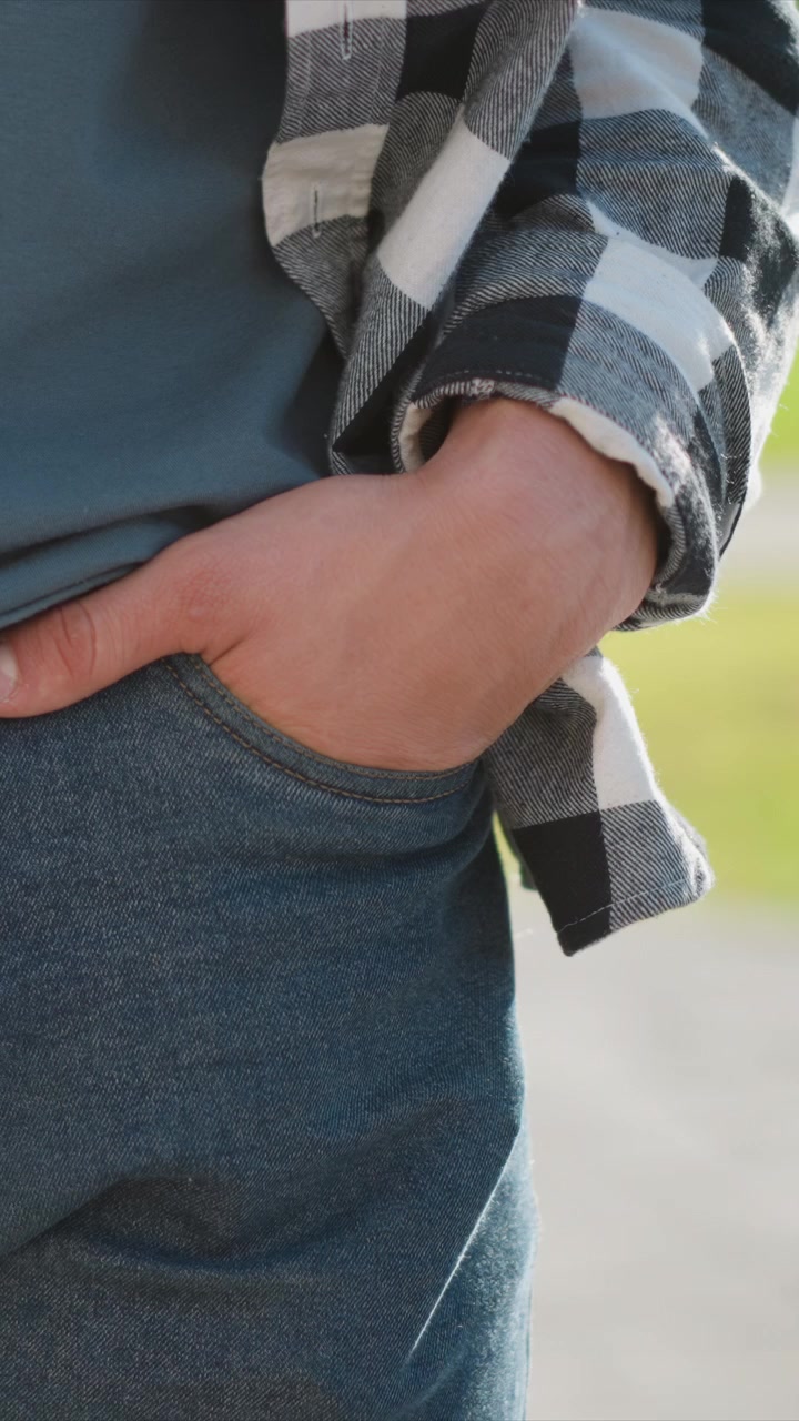 Close up of man hand resting in pocket wearing blue jeans and layered with denim jacket. scene focuses on texture detail including stitching patterns visible under soft lighting. Background