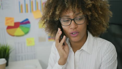 年轻女子在办公室用智能手机聊天