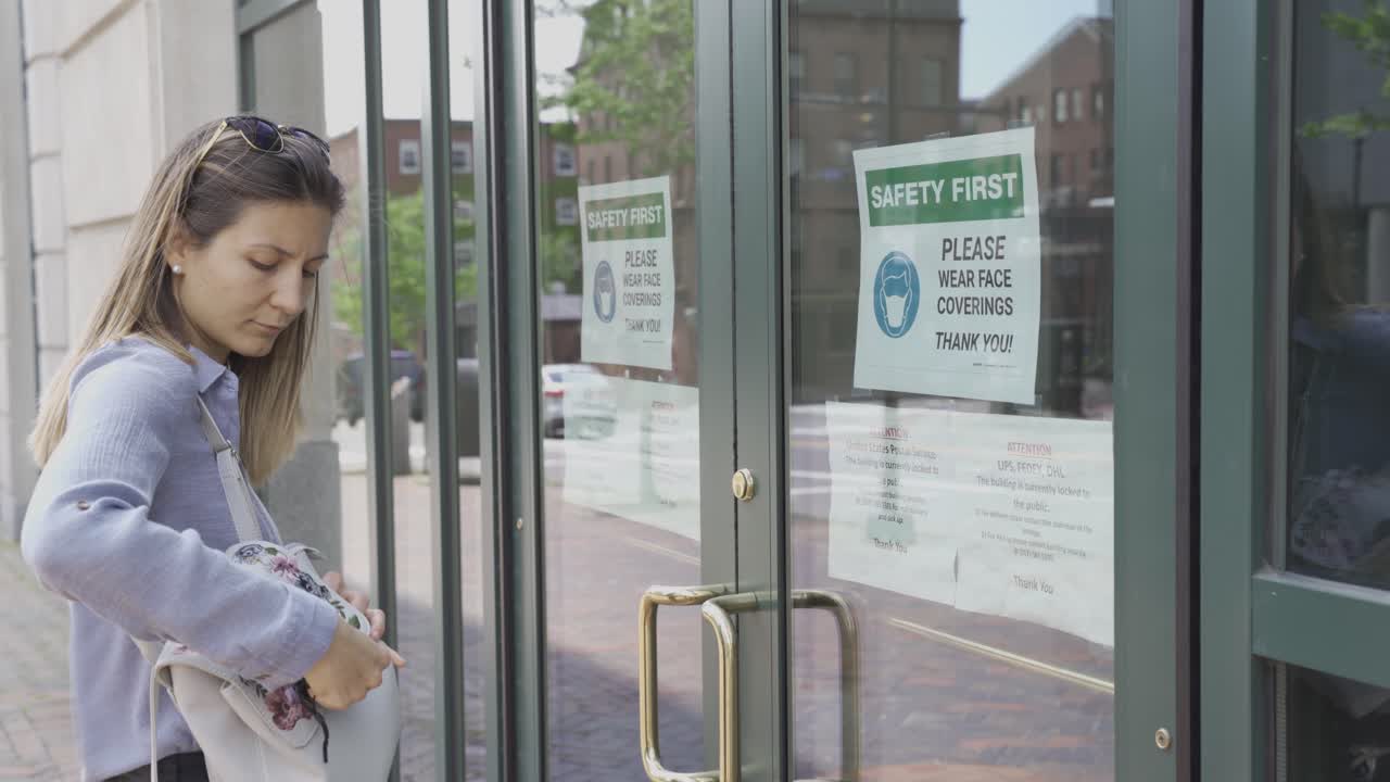 la ragazza legge il cartello con la scritta "sicurezza" sopra, si copre il viso con la maschera