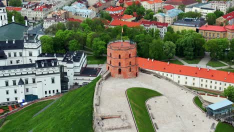 Volar-Sobre-La-Torre-Del-Castillo-De-Gediminas-Con-Bandera-Ondeante-En-Vilnius,-Lituania