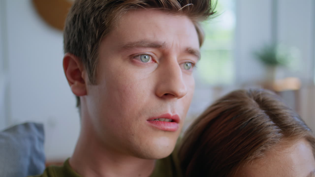 Sad man bonding girlfriend watching movie at sofa closeup. Couple looking tv