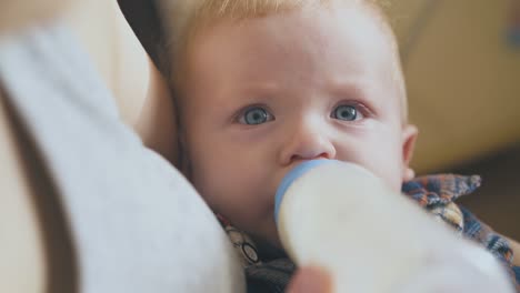 mother-feeds-little-baby-with-tasty-milk-mix-in-light-room