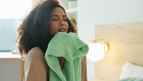 woman smelling a fresh sweater in bedroom