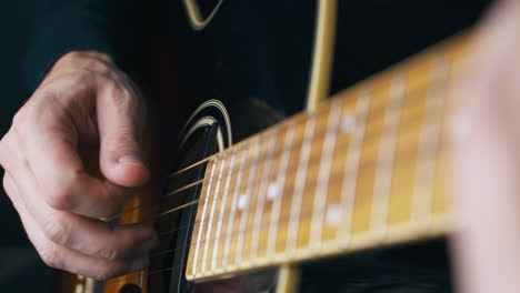 La-Persona-Toca-Una-Melodía-Tranquila-En-Una-Guitarra-Vieja-Con-Cuerpo-Negro.