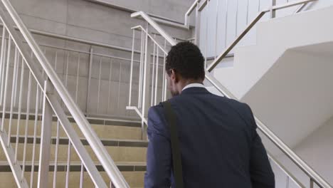 happy african american businessman going up stairs at office, slow motion