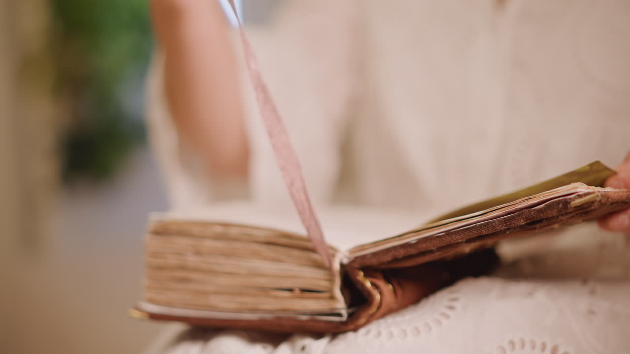 Donna caucasica che esamina il nastro di un libro antico, una mano attenta solleva un segnalibro di seta dalle pagine logore, primo piano sul dorso testurizzato e sulla pergamena, uno studio archivistico mirato, curiosità silenziosa e movimento metodico