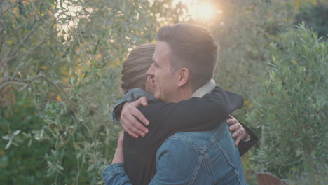 una pareja de jóvenes enamorados se reúnen y se abrazan al aire libre en el campo de otoño o invierno contra el sol abrasador