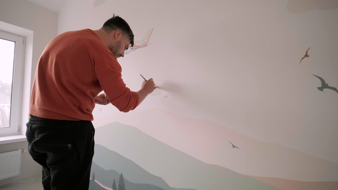 el artista está decorando las paredes con dibujos en la habitación de los niños. pintura de arte de las paredes en la casa nueva. trabajos de reparación.