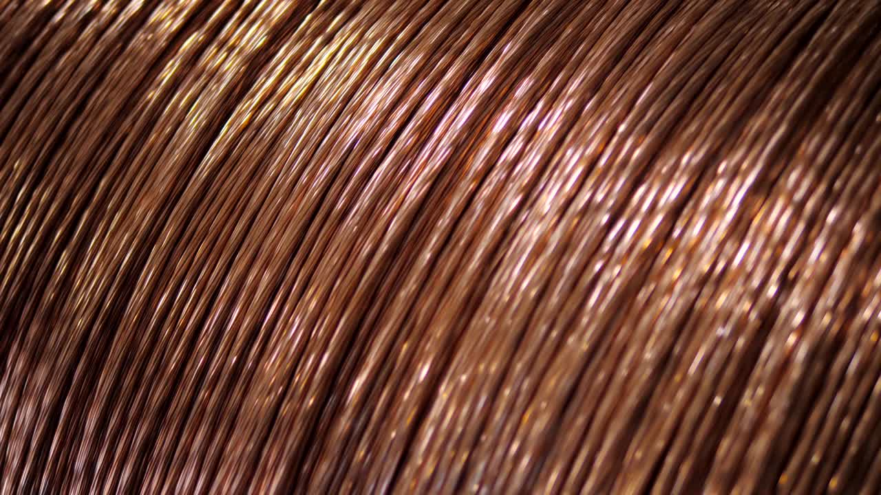 Close-up copper wire is wound on the large coil at the factory for the manufacture of electric cable.