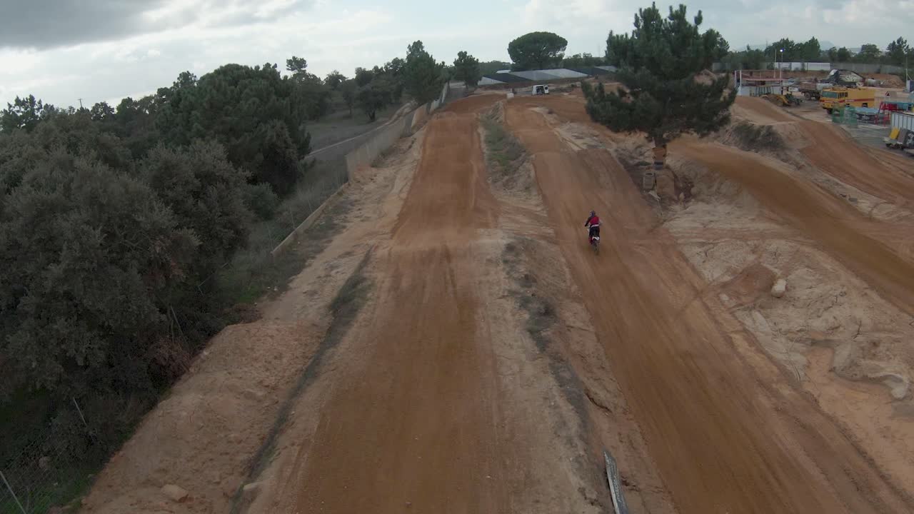 cámara lenta fpv aérea de pilotos de motocross épicos saltando en pista de tierra