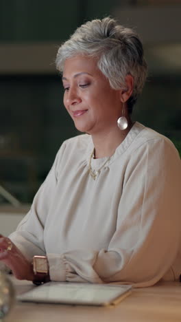 a woman smiling and working on her laptop at a desk.