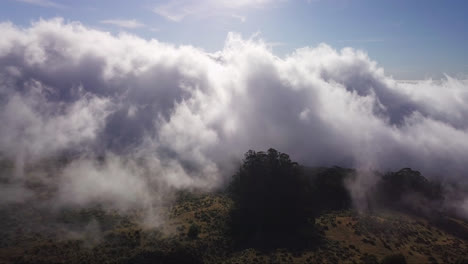 drone flyover view of white clouds moving over the mountain sides of the haleakala volcano