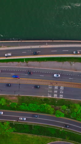 few roads going through the green bank of the river. aerial perspective on the motorways and cars going on. vertical video