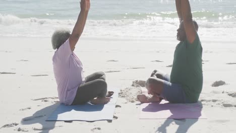 Feliz-Pareja-Afroamericana-Mayor-Haciendo-Yoga-Y-Meditando-En-La-Playa,-En-Cámara-Lenta