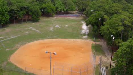 Tiro-Aéreo-De-Drones-Deslizándose-Sobre-Un-Campo-De-Béisbol-Vacío-En-El-Parque-En-Un-Día-Soleado