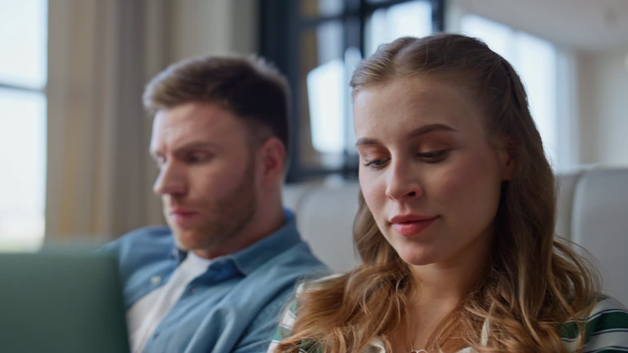 Spouses looking laptop screen sitting in living room closeup. Couple talking