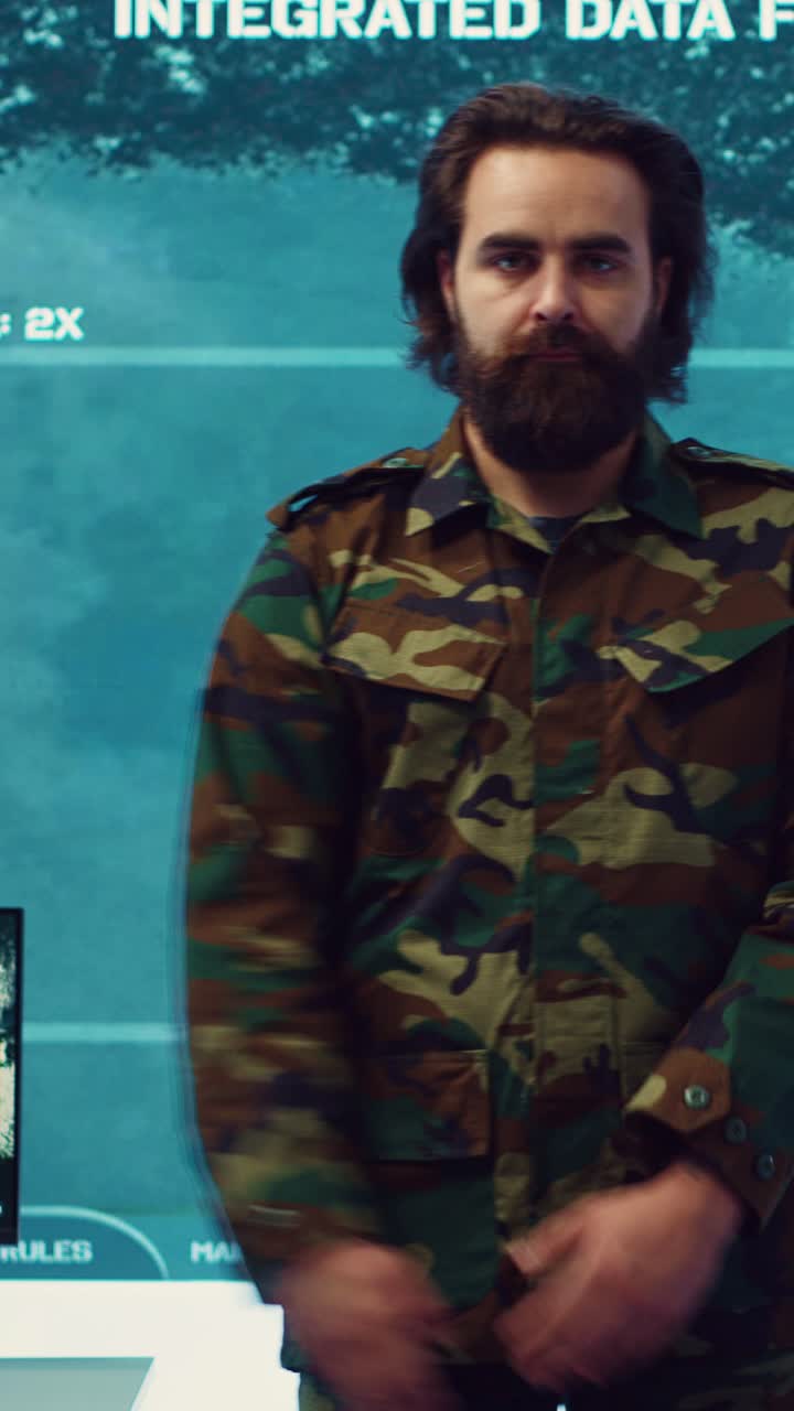 Bearded Man in Camouflage Uniform Saluting in Front of Data Screen
