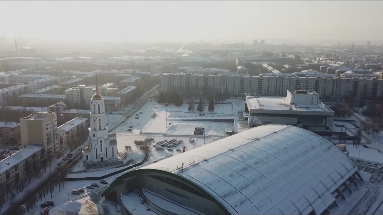 Sneklædt bybillede med kirke og sportsarena